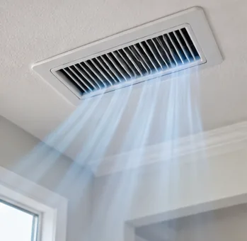 Close view of a white ceiling supply vent with air flowing into a room